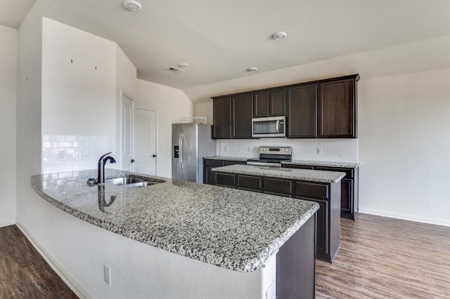 kitchen with sink, appliances with stainless steel finishes, backsplash, light stone counters, and kitchen peninsula