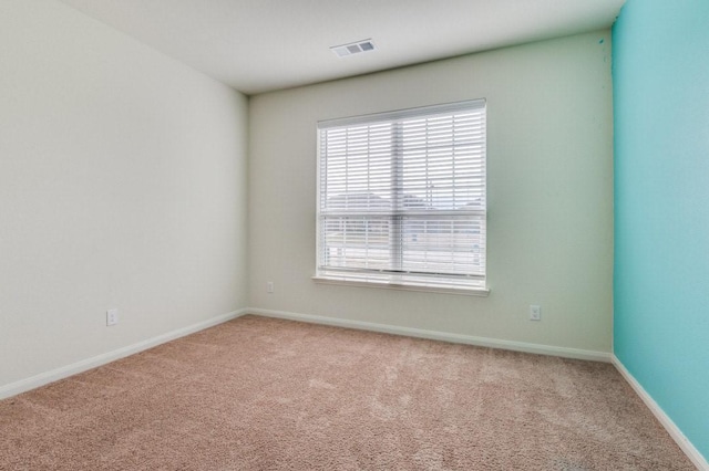 empty room featuring carpet floors, visible vents, and baseboards