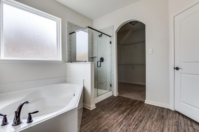 full bathroom with wood finished floors, a garden tub, a walk in closet, and a shower stall