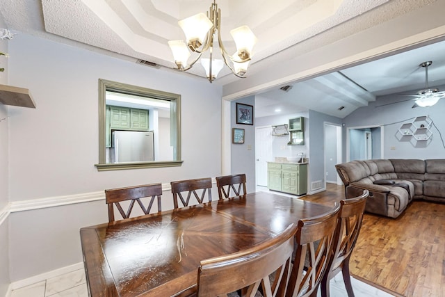 dining space with ceiling fan with notable chandelier, lofted ceiling, and light wood-type flooring