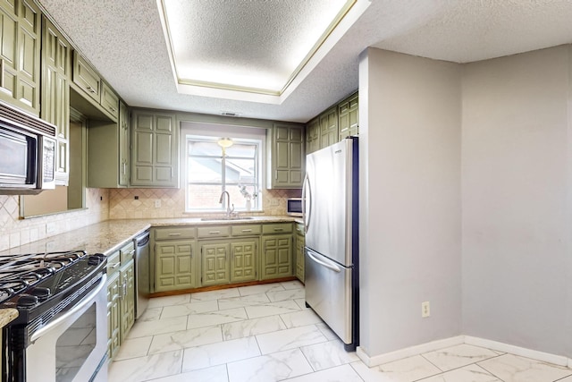 kitchen with decorative backsplash, sink, green cabinets, and appliances with stainless steel finishes