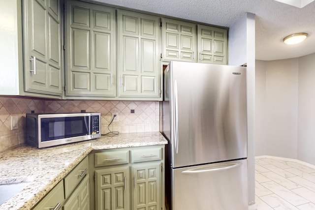 kitchen featuring light stone counters, green cabinets, appliances with stainless steel finishes, and a textured ceiling