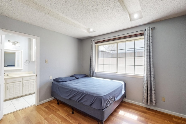 bedroom with hardwood / wood-style floors, a textured ceiling, and ensuite bath