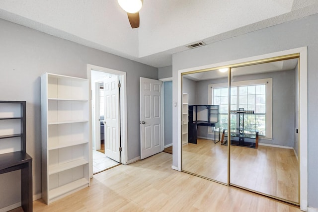 unfurnished bedroom with light wood-type flooring, a closet, and ceiling fan