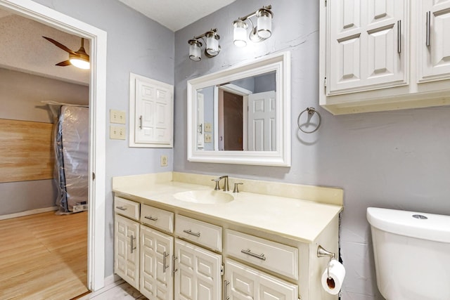 bathroom with toilet, ceiling fan, and vanity