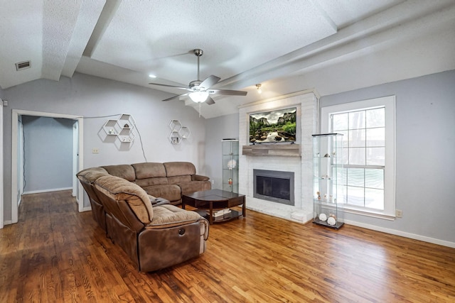 living room with hardwood / wood-style flooring, a brick fireplace, plenty of natural light, and lofted ceiling with beams