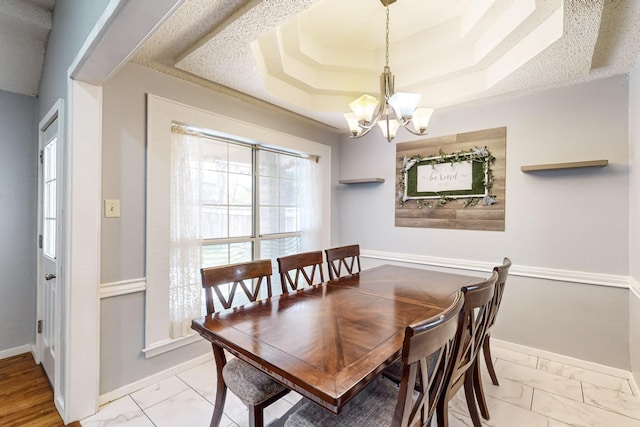 dining area featuring a notable chandelier and a tray ceiling