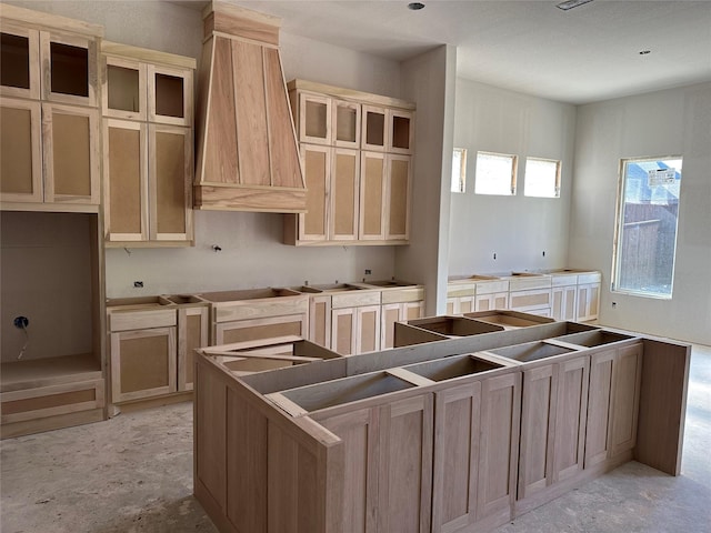 kitchen with light brown cabinets, black electric cooktop, a kitchen island, and custom exhaust hood