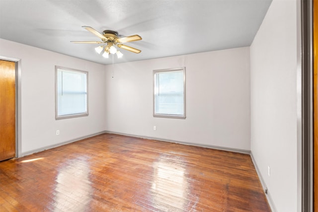 spare room featuring ceiling fan, a healthy amount of sunlight, and hardwood / wood-style floors