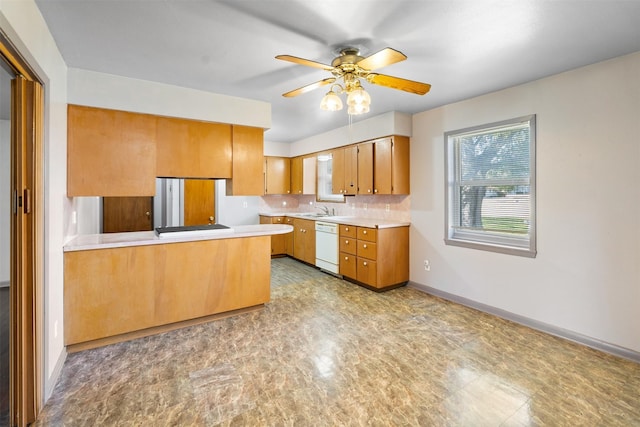 kitchen with kitchen peninsula, ceiling fan, white dishwasher, sink, and decorative backsplash