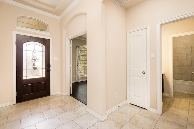 tiled foyer featuring a wealth of natural light and crown molding