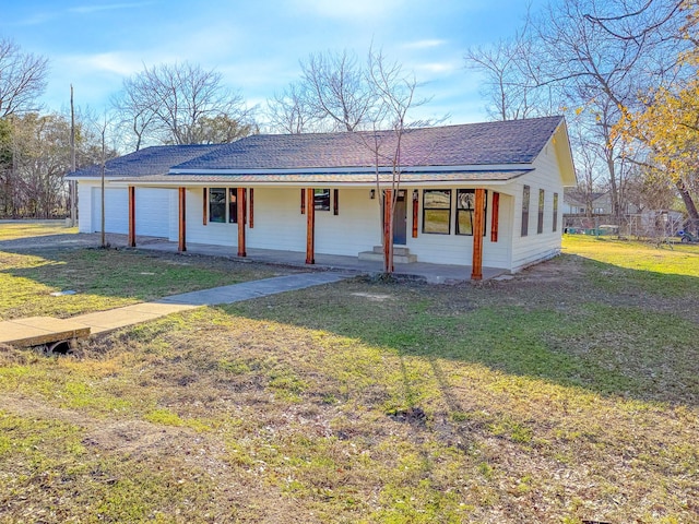 ranch-style house featuring a garage, covered porch, and a front lawn