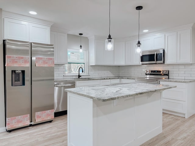 kitchen featuring sink, appliances with stainless steel finishes, white cabinetry, hanging light fixtures, and a center island