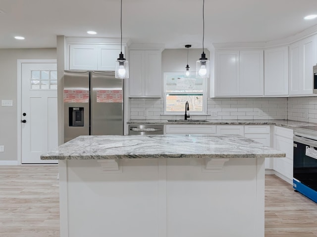 kitchen featuring pendant lighting, sink, stainless steel appliances, white cabinets, and a kitchen island