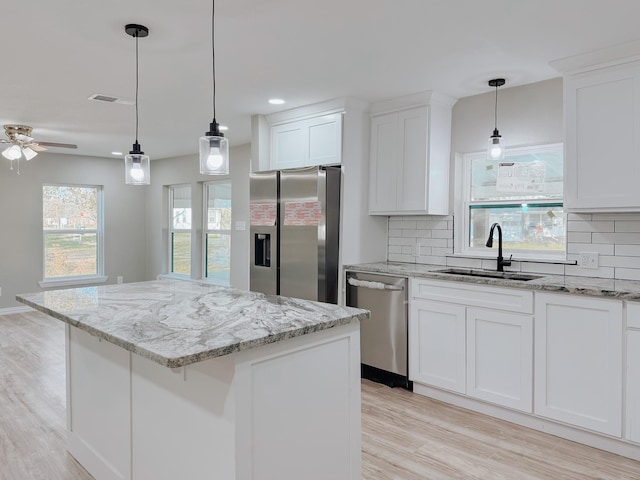 kitchen featuring backsplash, appliances with stainless steel finishes, a kitchen island, and white cabinets