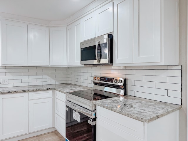 kitchen featuring light stone countertops, decorative backsplash, stainless steel appliances, and white cabinets