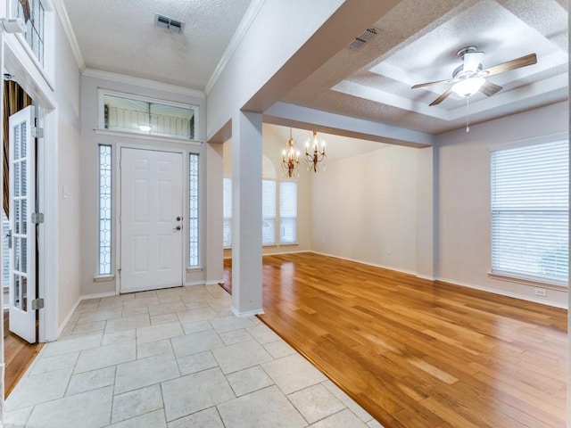 entryway featuring a tray ceiling, light hardwood / wood-style flooring, ornamental molding, and a textured ceiling