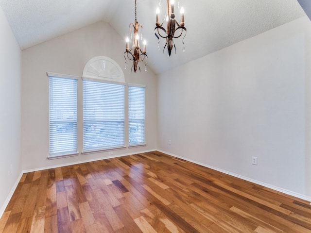 unfurnished room featuring an inviting chandelier, wood-type flooring, and lofted ceiling