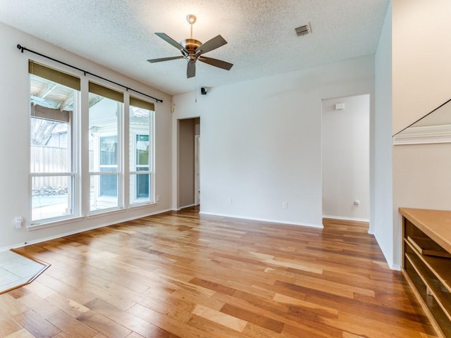 unfurnished living room featuring ceiling fan, light hardwood / wood-style floors, and a textured ceiling