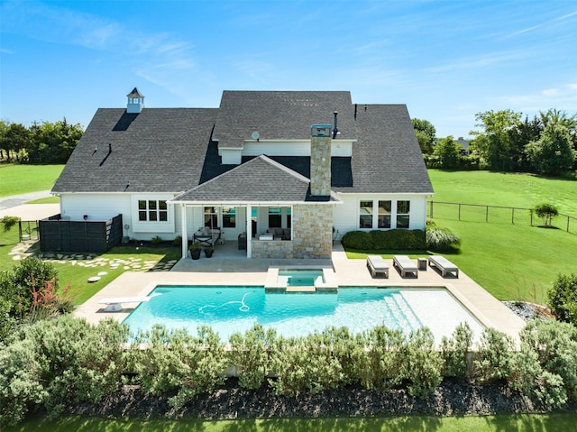 rear view of property with a patio area, a pool with hot tub, and a yard