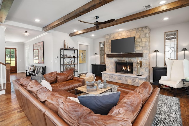 living room with ceiling fan, wood-type flooring, and a stone fireplace