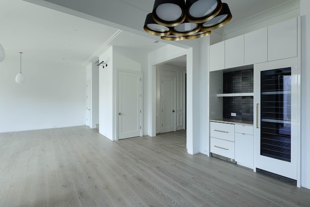 interior space featuring hanging light fixtures, white cabinets, light wood-type flooring, and wine cooler