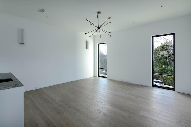 unfurnished living room with light wood-type flooring and a chandelier