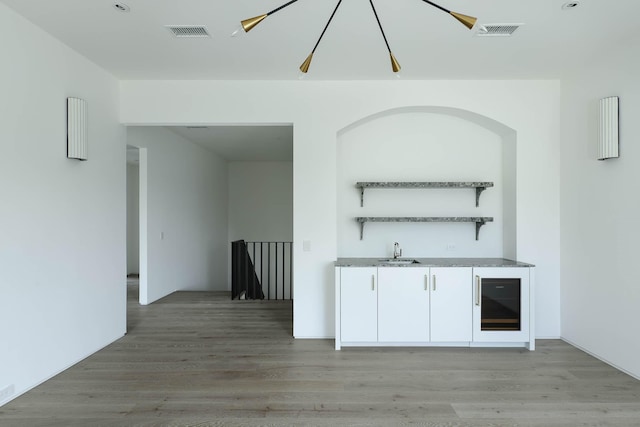 bar featuring sink, white cabinets, beverage cooler, and wood-type flooring