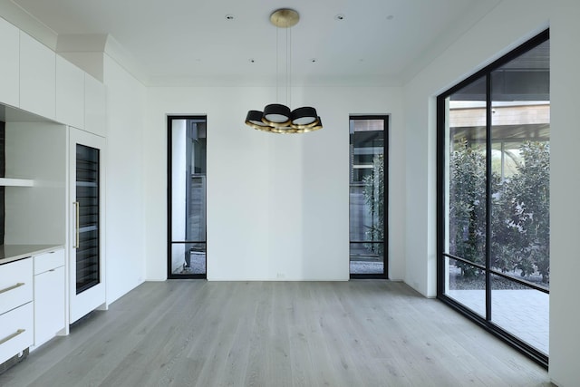 unfurnished room featuring light wood-type flooring and a notable chandelier