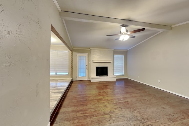 unfurnished living room with a fireplace, wood-type flooring, ornamental molding, ceiling fan, and lofted ceiling with beams