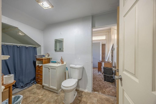 bathroom with toilet, vanity, and lofted ceiling