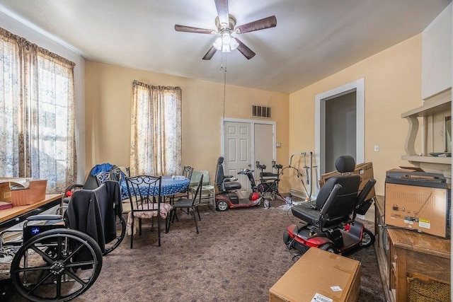 misc room featuring ceiling fan, a healthy amount of sunlight, and dark colored carpet