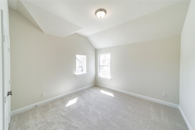 carpeted spare room with lofted ceiling