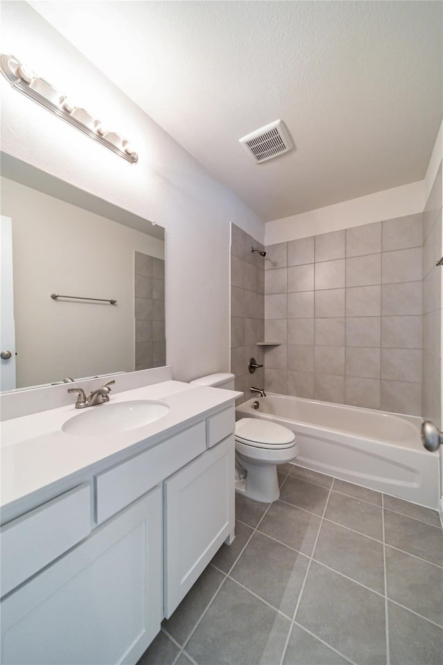 full bathroom featuring toilet, tiled shower / bath, a textured ceiling, vanity, and tile patterned flooring