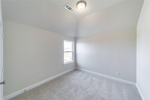 carpeted spare room with vaulted ceiling