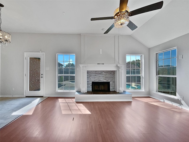 unfurnished living room with hardwood / wood-style flooring, a stone fireplace, ceiling fan, and lofted ceiling