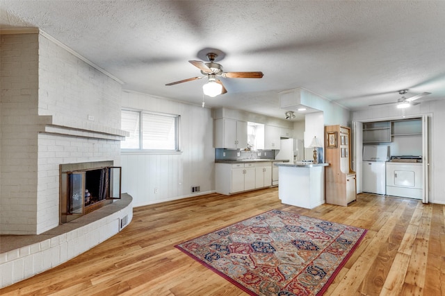 kitchen with white refrigerator with ice dispenser, washer / clothes dryer, light wood-type flooring, white cabinetry, and a textured ceiling