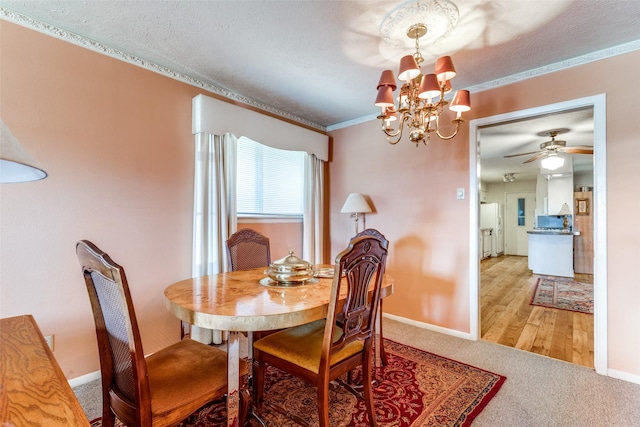 dining space featuring ceiling fan with notable chandelier, light colored carpet, a textured ceiling, and ornamental molding