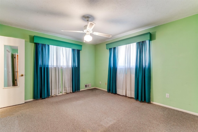 carpeted spare room featuring ceiling fan and a textured ceiling