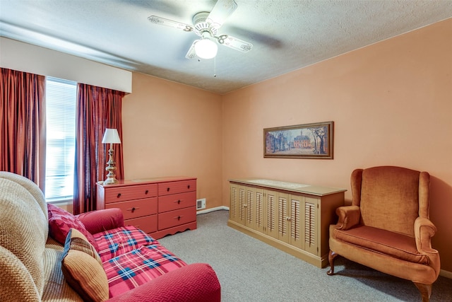 sitting room with ceiling fan, light colored carpet, and a textured ceiling