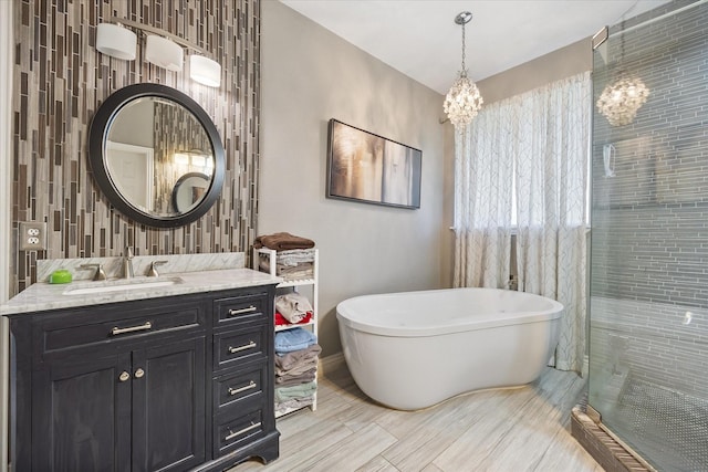 bathroom with vanity, an inviting chandelier, and shower with separate bathtub