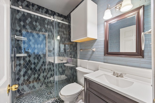 bathroom featuring a shower with door, toilet, tile walls, and vanity