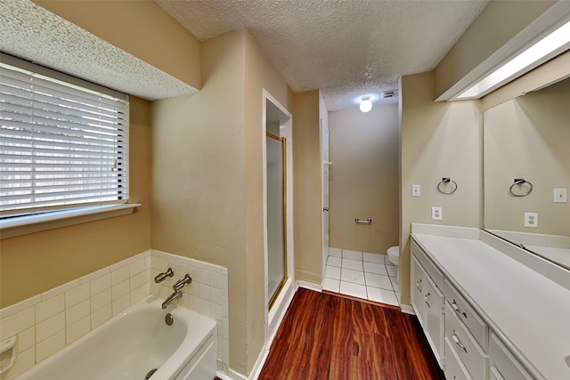 full bathroom with wood-type flooring, vanity, a textured ceiling, and plus walk in shower