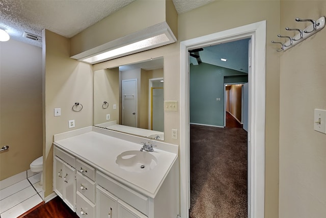 bathroom with a textured ceiling, toilet, and vanity