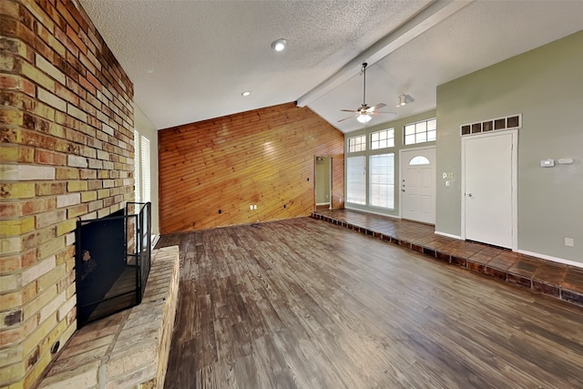 unfurnished living room featuring a textured ceiling, light hardwood / wood-style floors, lofted ceiling with beams, and a fireplace