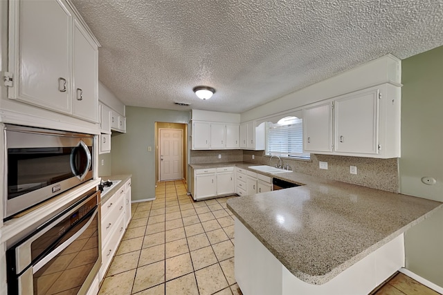 kitchen with kitchen peninsula, sink, white cabinetry, and appliances with stainless steel finishes