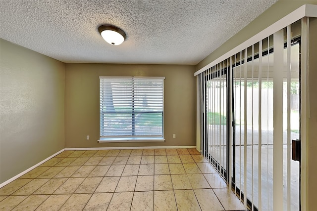 empty room featuring a textured ceiling and light tile patterned floors