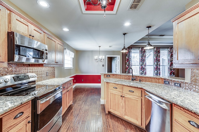 kitchen featuring kitchen peninsula, sink, decorative light fixtures, decorative backsplash, and stainless steel appliances