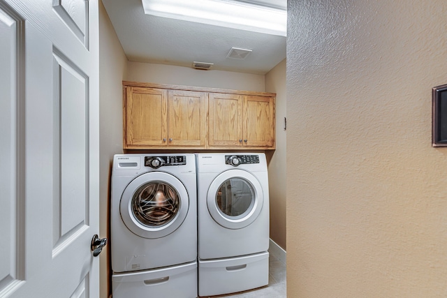 laundry room featuring independent washer and dryer, cabinets, and light tile patterned flooring