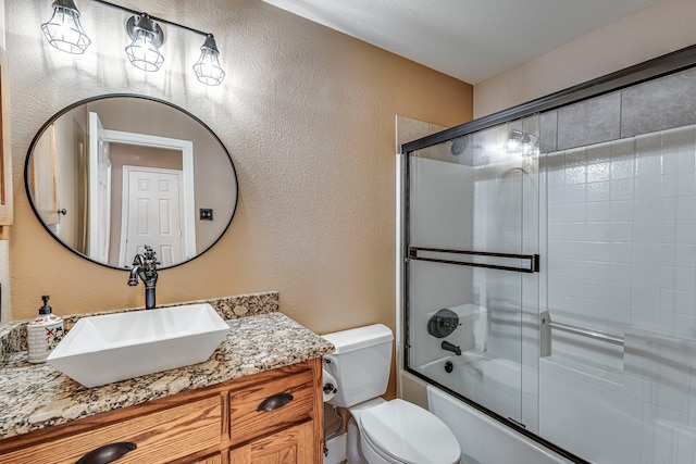 full bathroom featuring combined bath / shower with glass door, vanity, and toilet